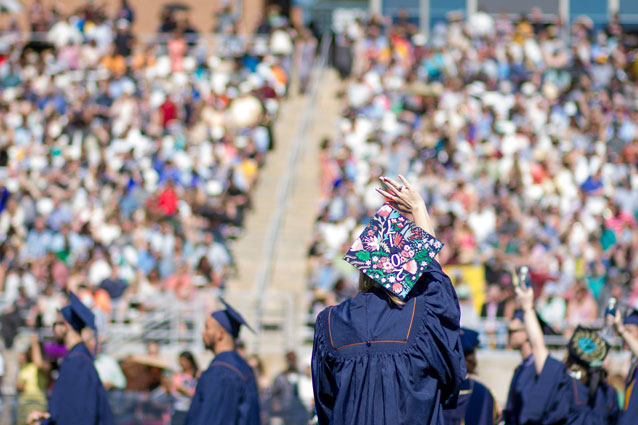 A student waves to families at UNC's commencement on Nottingham Field