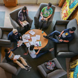 Students do homework and socialize in comfy chairs around a circular table