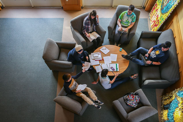 College students relax and do homework together gathered around a table