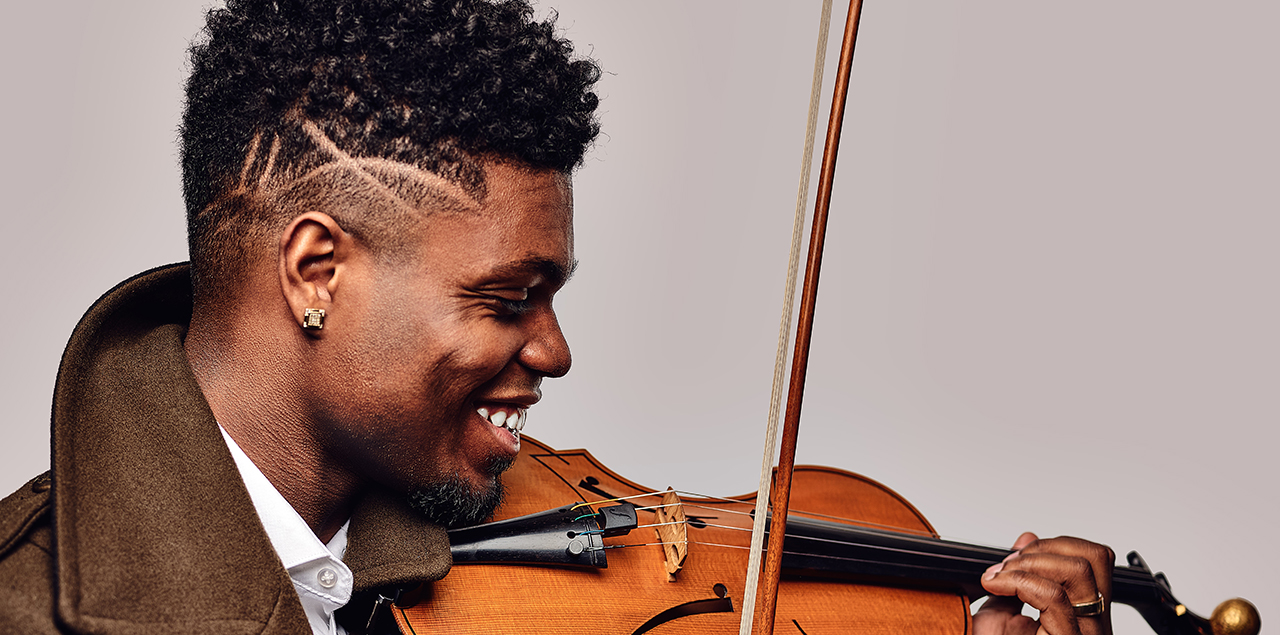 Profile of Edward Hardy holding a violin and smiling