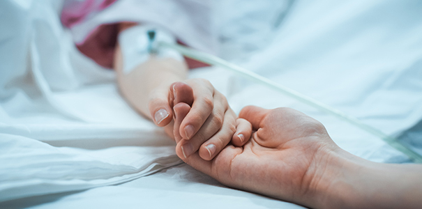 Parent holding kid's hand in hospital bed