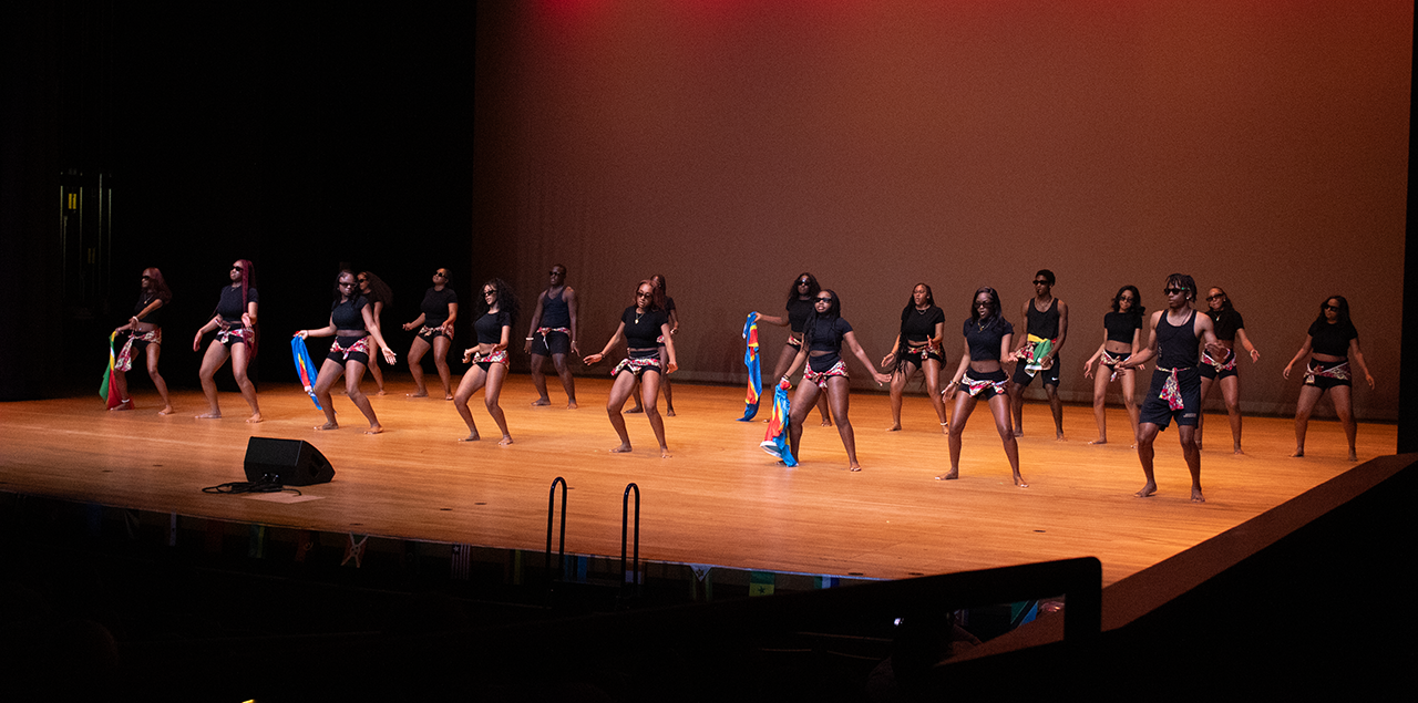 Men and women wearing black dancing in unison on a stage
