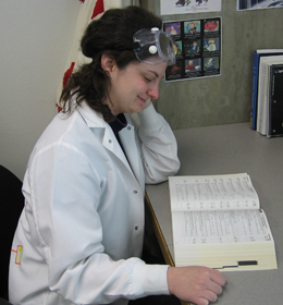 Courtney Rayley sitting at a desk reading a text book while in a white lab coat.
