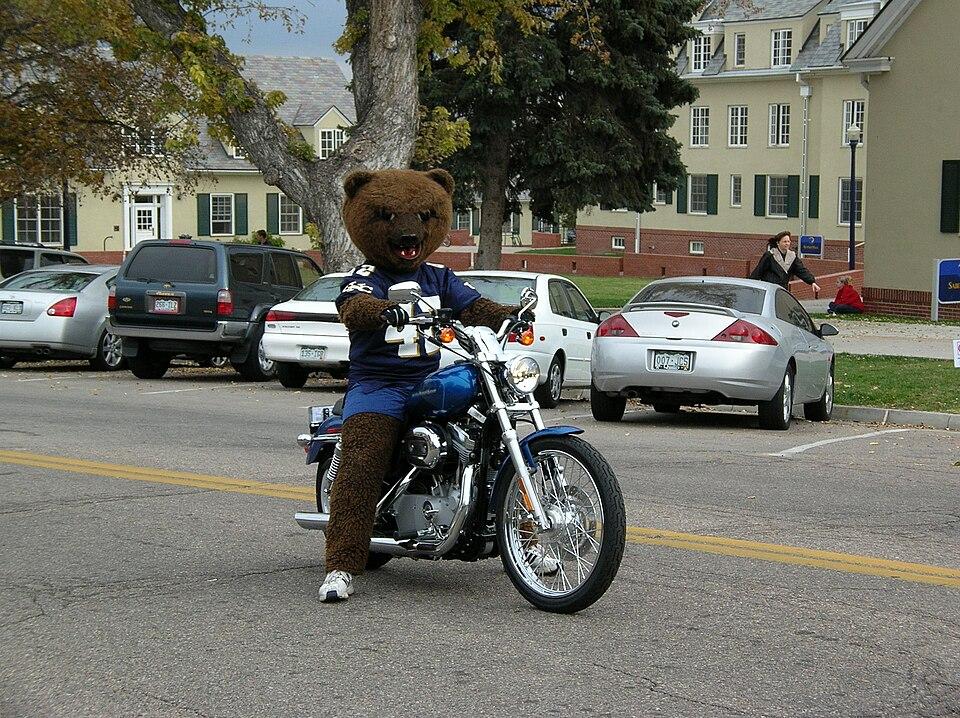 Klawz riding a motorcycle in the Homecoming Parade, 1990s