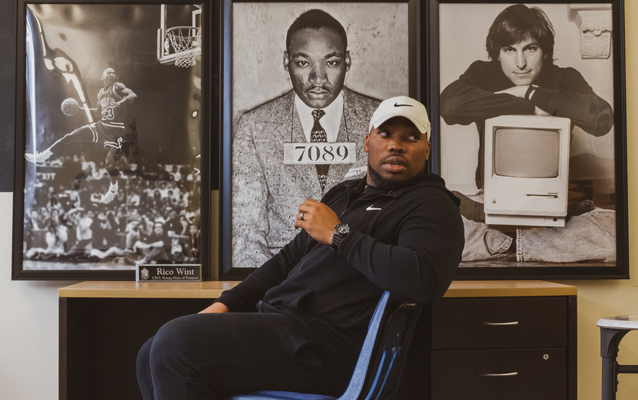 Rico Wint sits in front of large framed photos of Michael Jordan, Martin Luther King Jr., and Steve Jobs