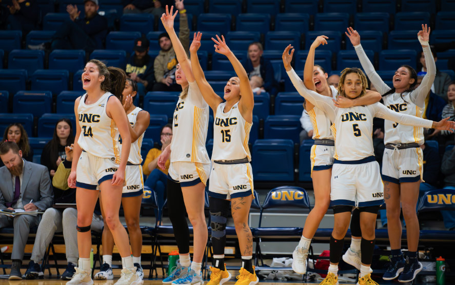 Group of women's basketball players celebrate on the basketball court during a game.