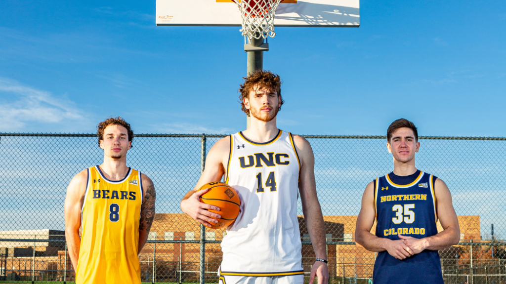 Three UNC basketball players in different UNC jersey's standing with serious faces