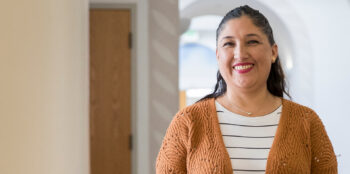 Claudia Hernandez standing inside Kepner Hall smiling