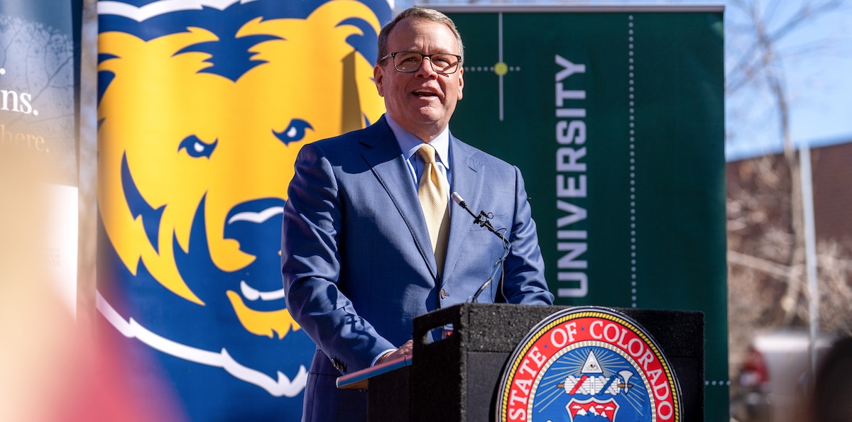 President Andy Feinstein standing outside behind a podium speaking to a crowd about the proposed legislation