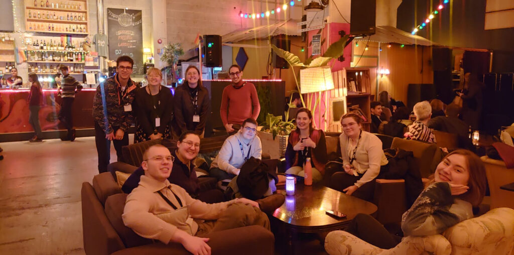 Dechant and Nichol sitting with a group of students in a hotel lobby