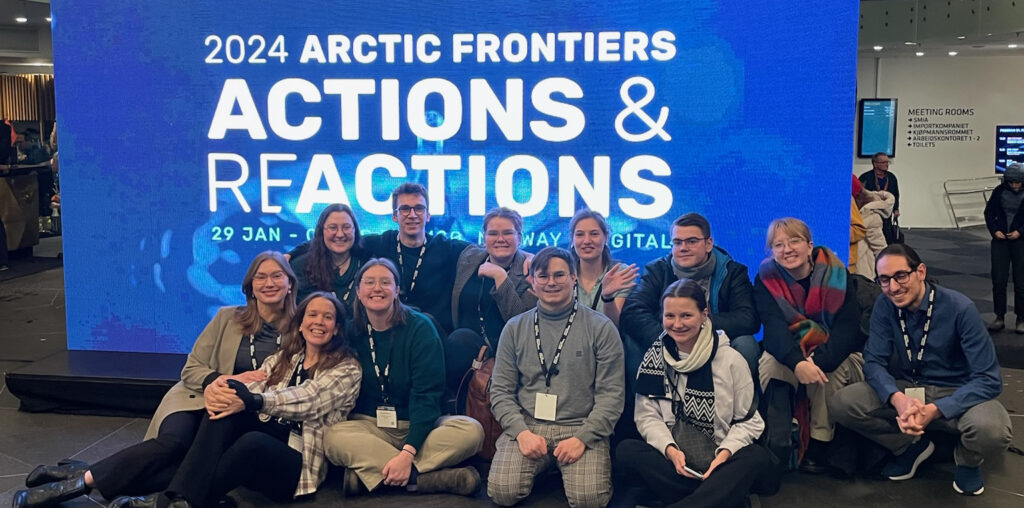 Group of students sitting on the floor in front of Arctic Frontiers sign