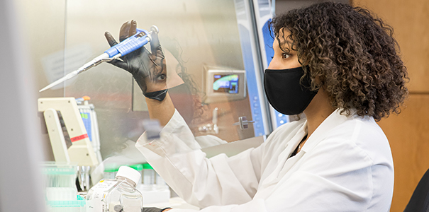 Female college student wearing a white robe in a biology lab
