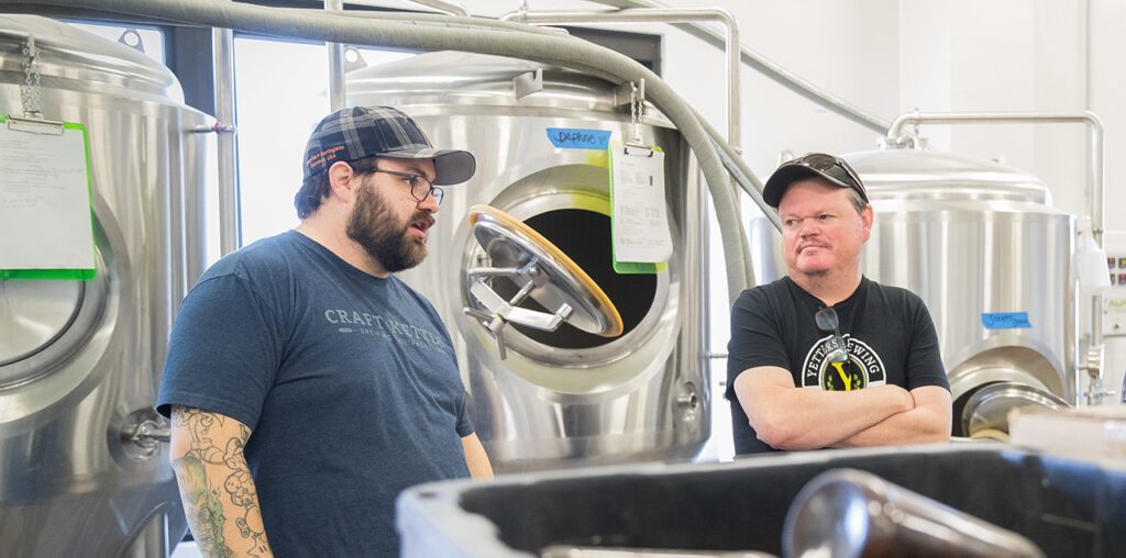 Sean Johnson and Dan Yetters standing and talking in the brewery.