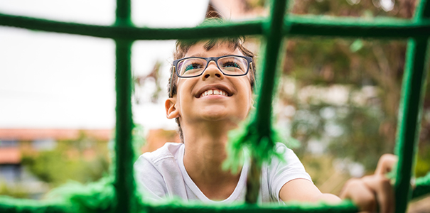 male child smiling and climbing playground equipment