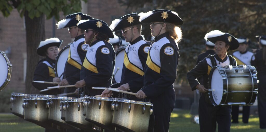 Members of the Pride of the Rockies marching band getting others excited and ready before their performance in Lincoln Park.