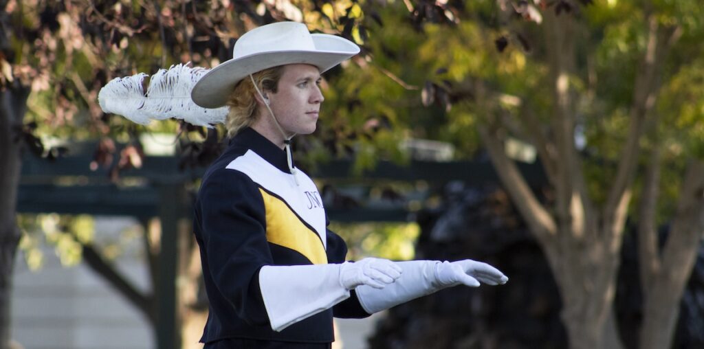 The conductor leading the marching band for its opening song