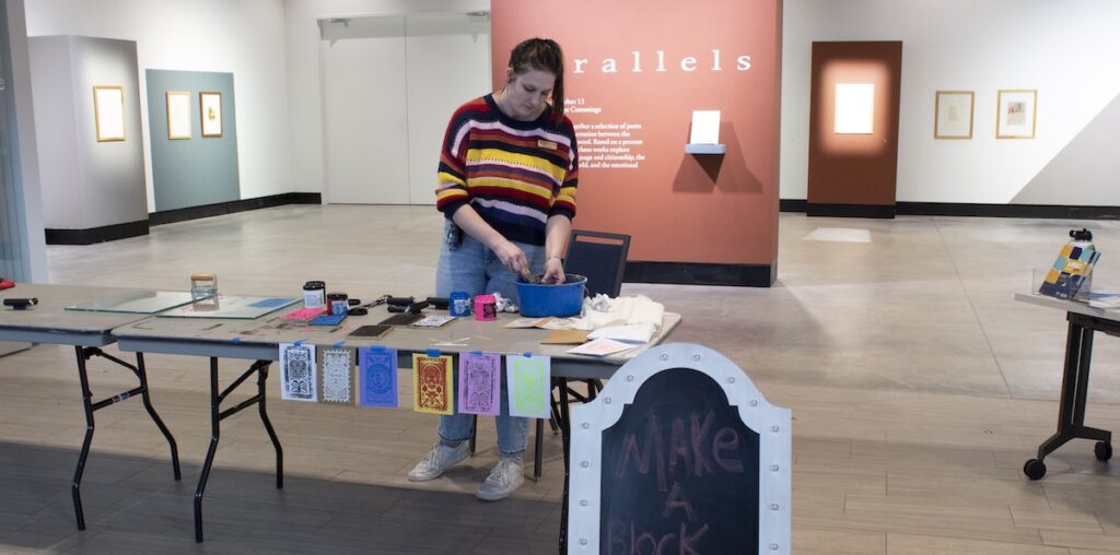 Catherine Cummings helping participants make a block print card by showing them the process it takes to make a block print.