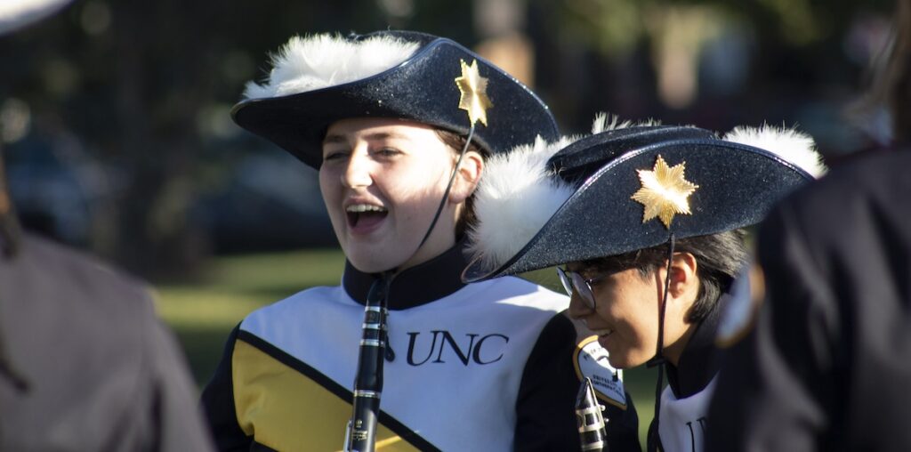 Members of the Pride of the Rockies marching band getting others excited and ready before their performance in Lincoln Park.