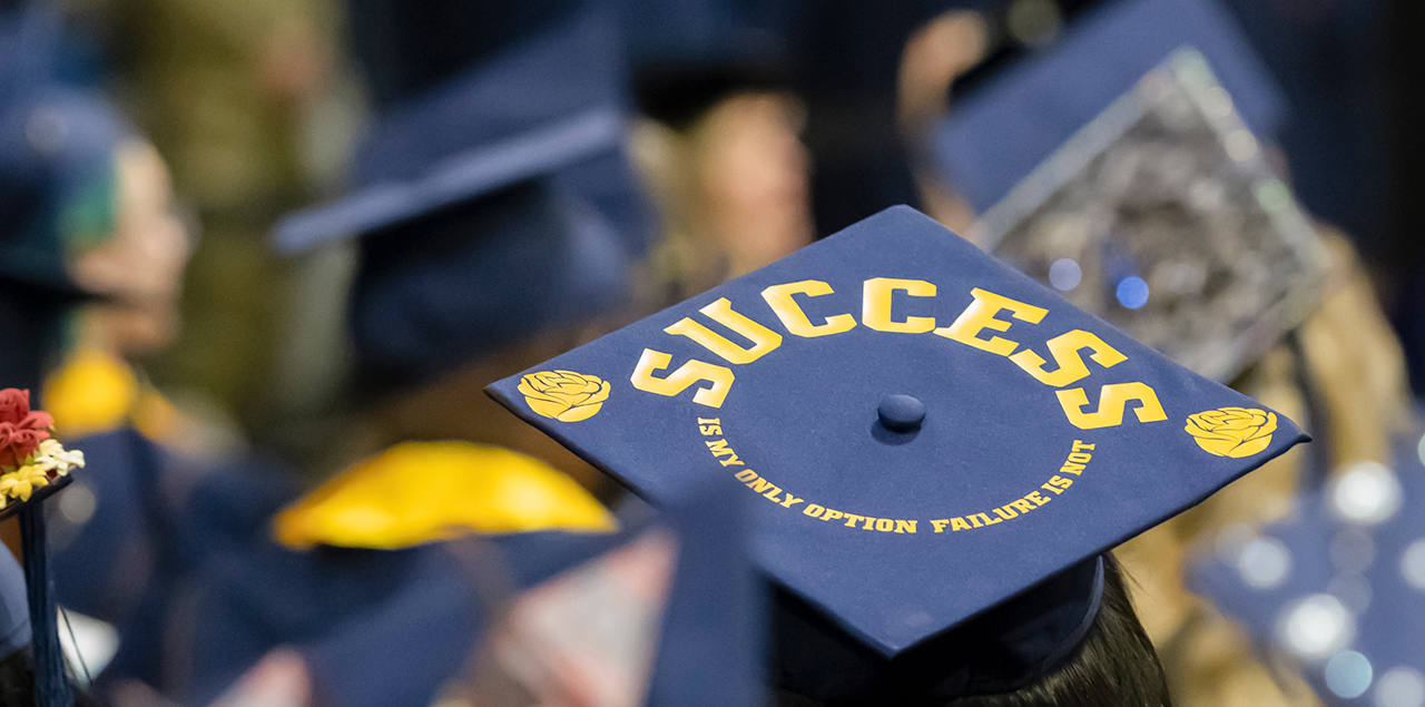 A photo showing the back of a blue graduation cap with the word success written on it.