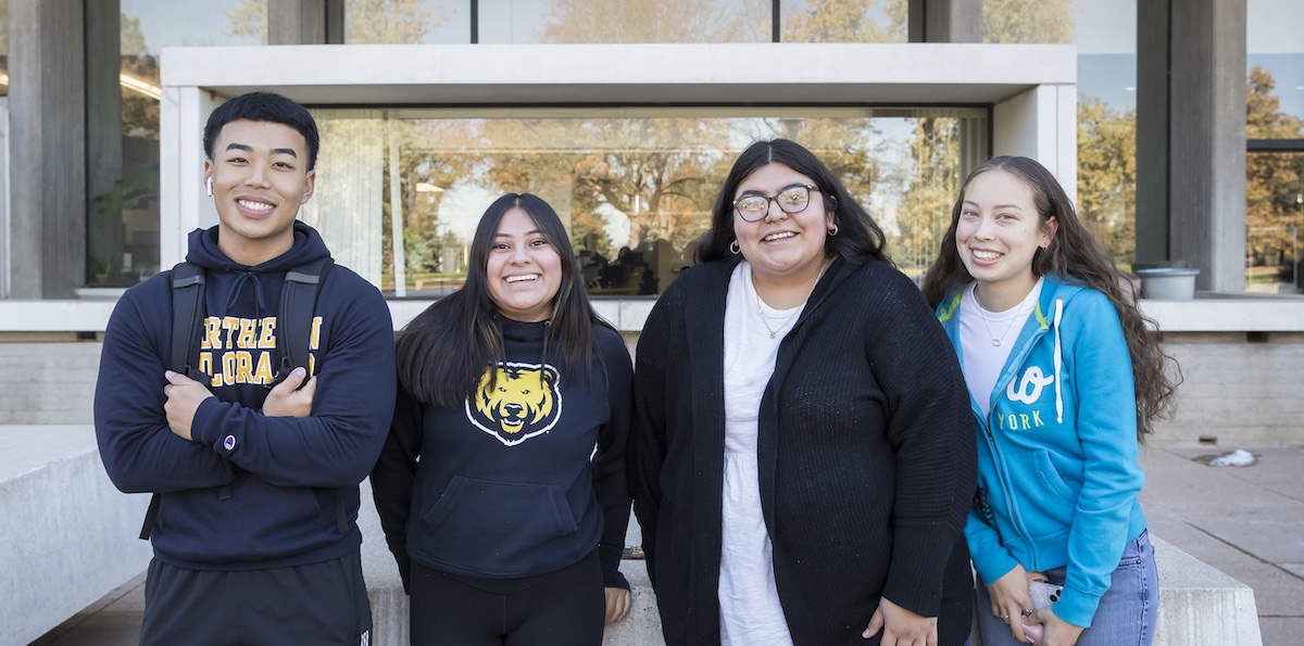 Four college students standing together outside smiling