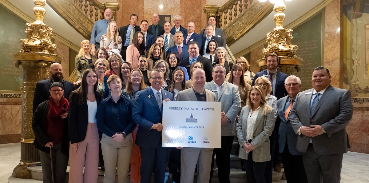 A group holding a Greeley Day at the Capitol sign in front of steps