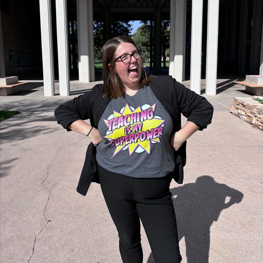 Holly Hyman smiling wide outside with her hands on her hips