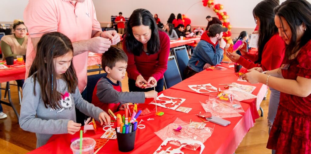 A child and her parents making crafts at a table