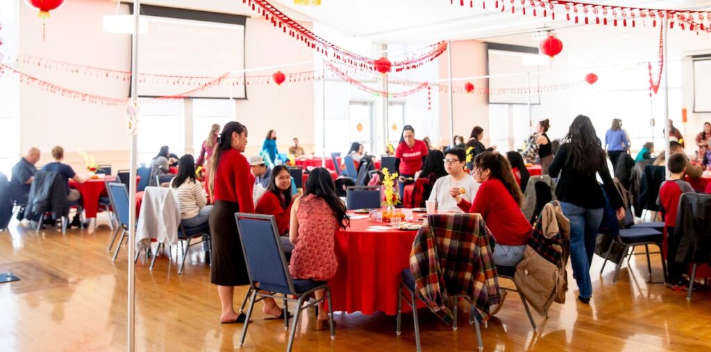 People sitting around tables with red table cloths