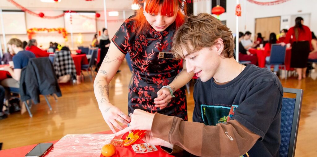 A woman helping a male student make crafts