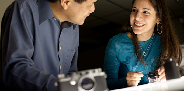 Professor talking with smiling female college photography student