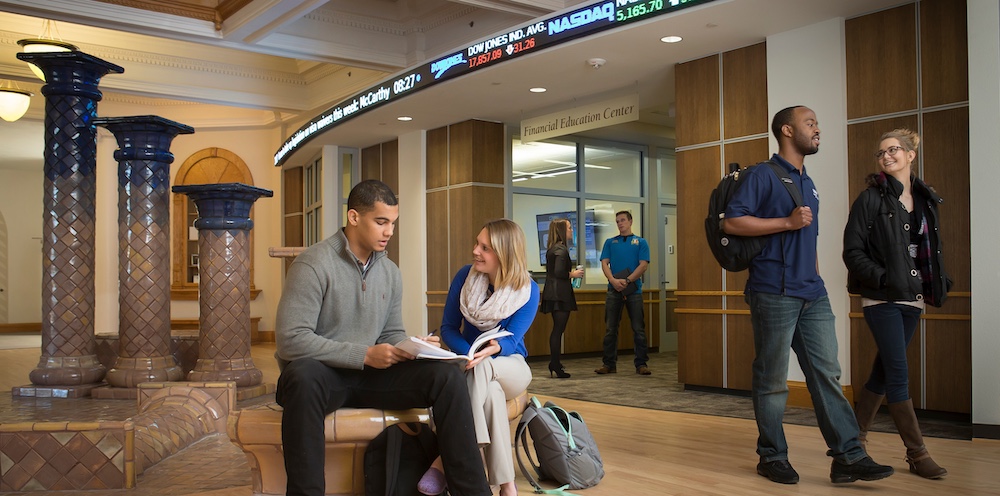 Students sitting inside college building talking to faculty member