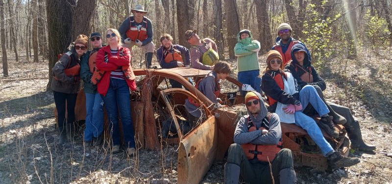 UNC students standing next to a beat up car near the Mississippi River