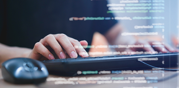 Close up of hands on a computer keyboard with computer code superimposed over the image