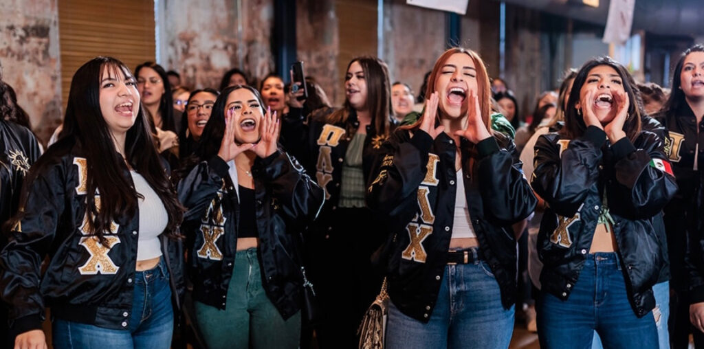 Four UNC students holding up their hands mid shout