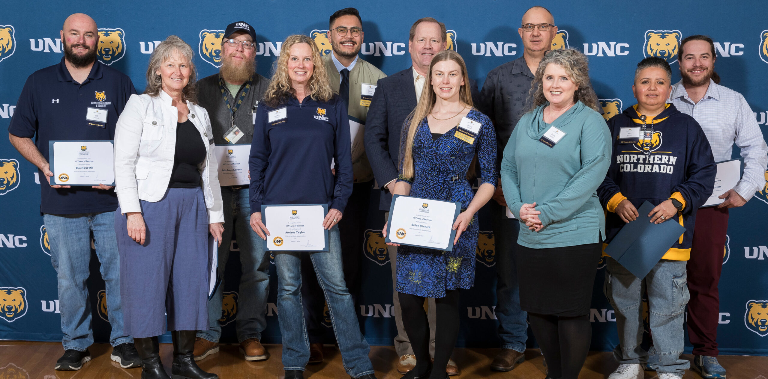 A group of staff members holidng up award certificates and smiling