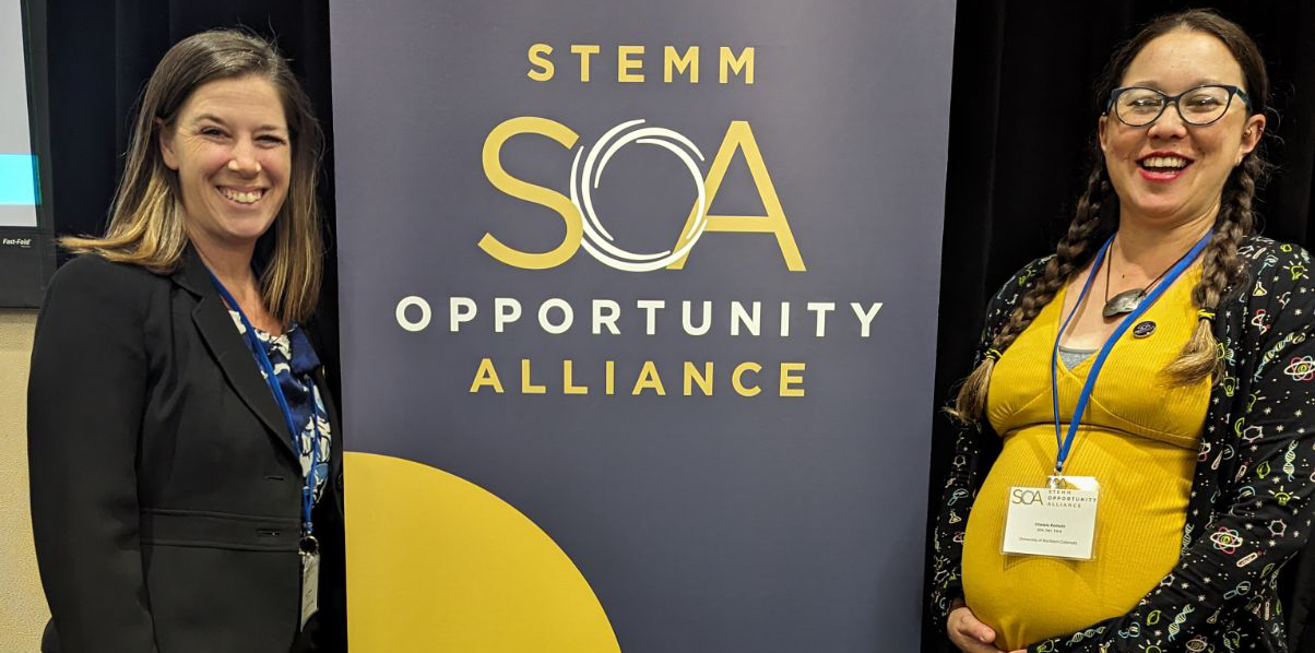 Harmony and Chelsie standing in front of a conference sign