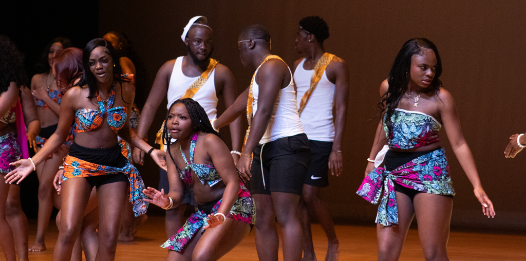 A group of men and women on stage dancing together