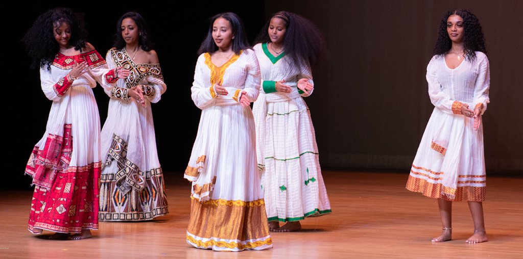 A woman wearing a white gown dancing on a stage