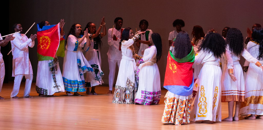 A group of dancers holding up flags and spinning each other