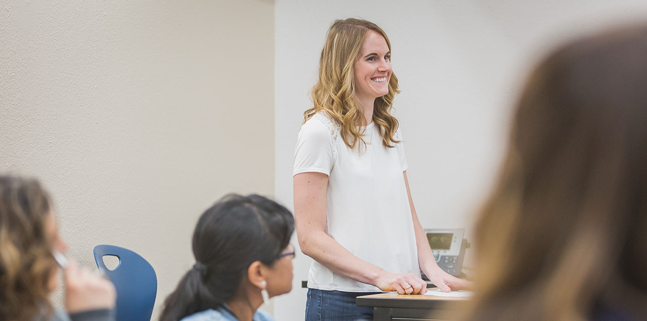 A UNC Alumna standing in a classroom