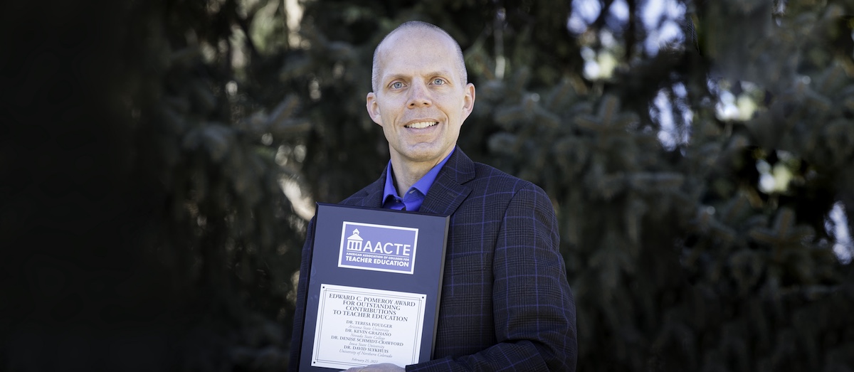 David holding the award plague on campus