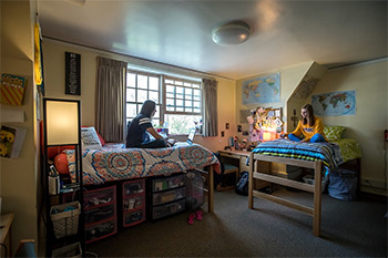 two students sitting on their beds in their own decorated dorm within Belford Hall