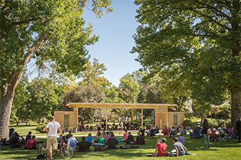 Many students sitting on the lawn in the open area in front of the Garden Theatre