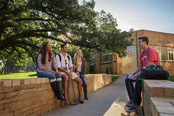 Students sitting on the short brick walls in front of Gray Hall