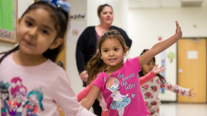 Young elementary chidren "flying" as they walk down the hall