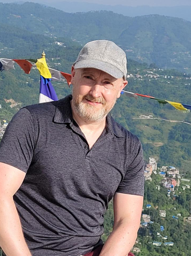 Photo of Richard Bownas outside with a backdrop of Nepal.