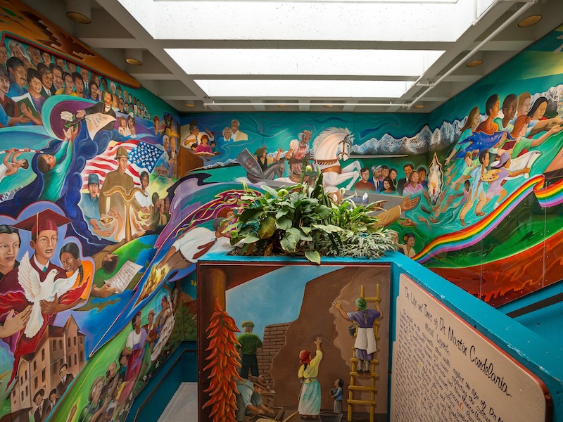 colorful wall mural depicting the life of Dr. Martin Candelaria, the building's namesake.