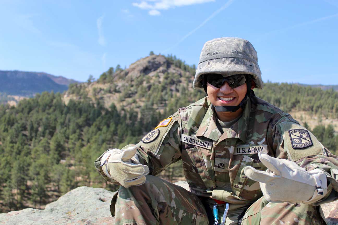 An enlisted soldier wearing full gear posing for a photo outside in the mountains.