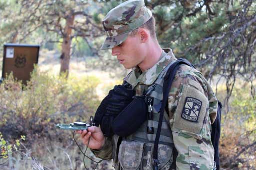 An ROTC person outside looking down at a compass in their hand