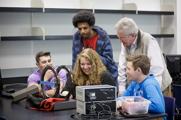 Professor assisting students with lab equipment.